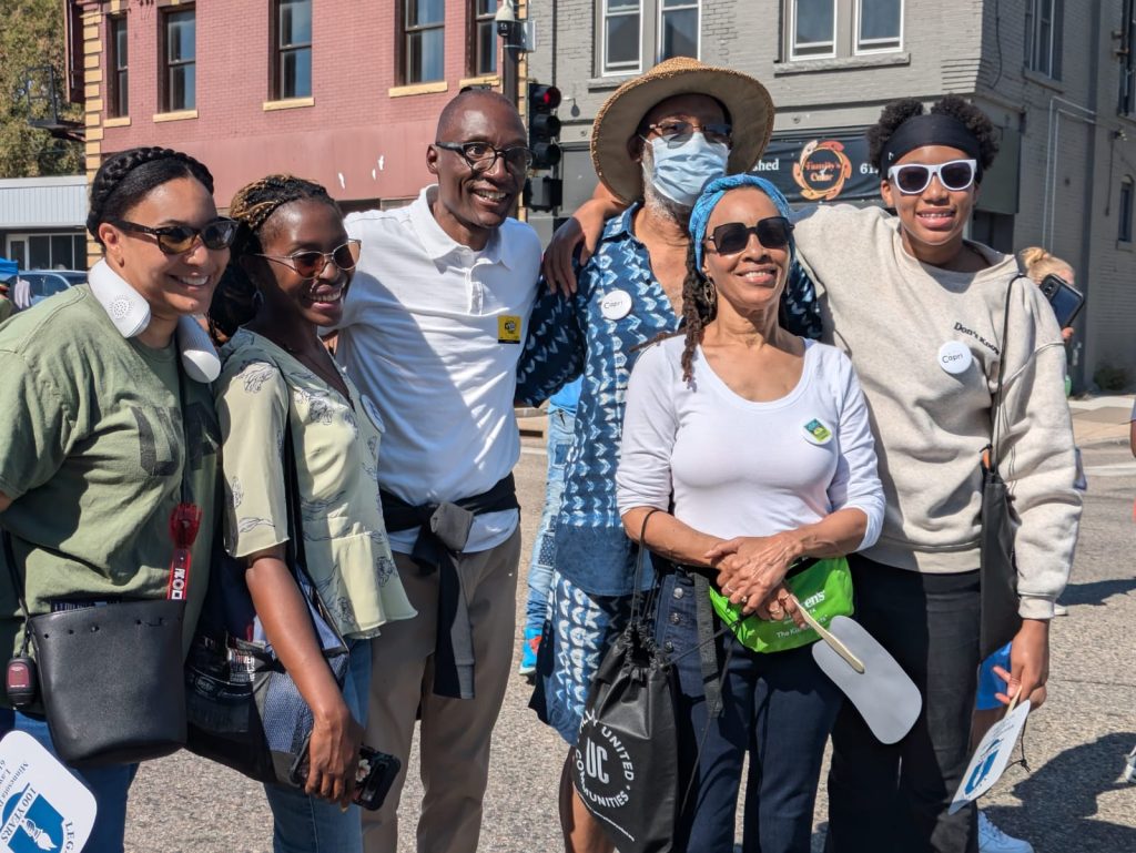 Esther standing and smiling with a group of people outdoors.
