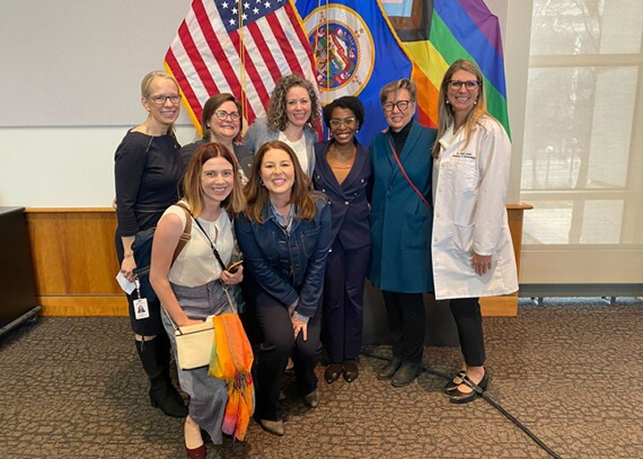 Esther standing with a group of women in front of three flags.